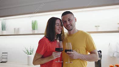 A joyful couple is happily celebrating their special moment together in a modern kitchen while raising glasses of wine