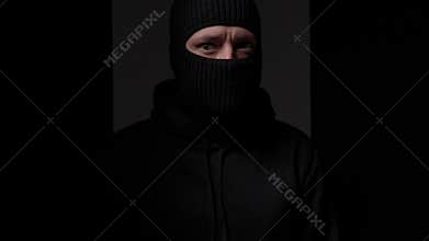 Masked person in dim light with intense gaze