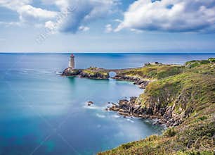 Bretagne coastline with lighthouse and blue ocean under clouds at midday near Brest