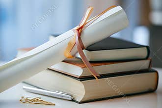Books Stacked Together With Ribbon and Rolled Paper Beside Pen and Colorful Clips on Table