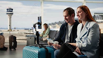 Content creators couple, filming vlog, in airport terminal with tripod