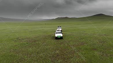 Two white offroad vehicles cross a treeless plateau on remote steppe safari terrain, suv, convoy, grassland, highland