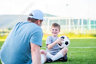 Dad and son having fun while practicing football outdoors.