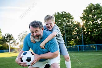 Dad and son having fun while practicing football outdoors.