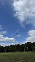 Small passenger airplane descending over grassy field beneath bright blue sky