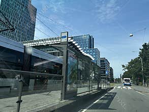 Modern tram stop beside glass office towers and wide city road in