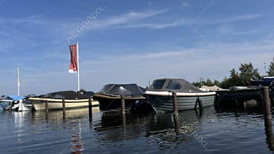 Moored leisure boats on calm marina water with clear blue sky, soft