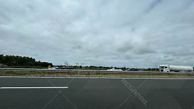 Wide highway view with moving traffic, tanker truck, cars, guardrail, open
