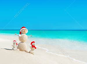Snowmen family at tropical beach in santa hats. New Years and Ch