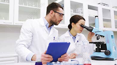 Scientists with tablet pc and microscope in lab