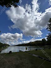 Wide river landscape with dramatic clouds, tree lined banks, grassy shoreline