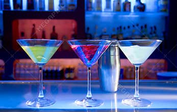 Three Colorful Cocktails on a Bar Counter in a Nightlife Setting