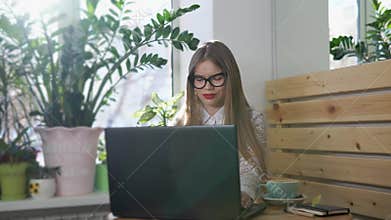 Young pretty business woman working behind her laptop in a bright room.