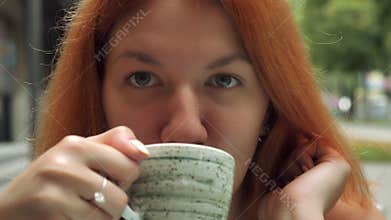 Redheaded millennial women enjoy drink at the open air.