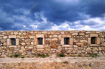 Beautiful old beige stone wall on the background of bright blue sky in Rethymnon, Crete