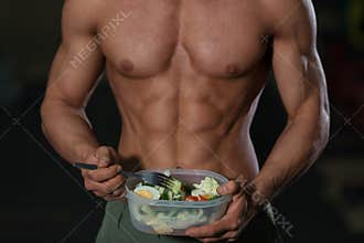 Close up of man athlete with vegetables.