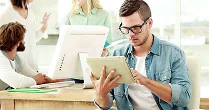 Casual businessman using tablet in front of colleagues