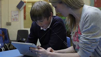Teacher Working With Male Pupil At Desk