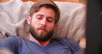 Man Watching Television At Home Then Answering Mobile Phone