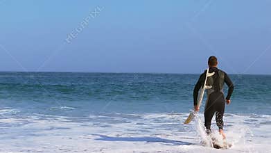 Man in wet suit running into water