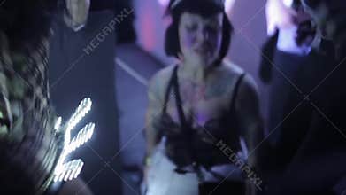 Tattoo woman of small growth in lace underwear dance in nightclub.
