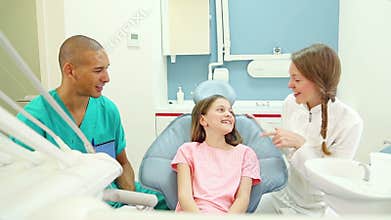 Lovely girl shows aching tooth to dentist and assistant, assistant exams her