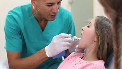 Close up of girl in dental chair shows with finger aching tooth