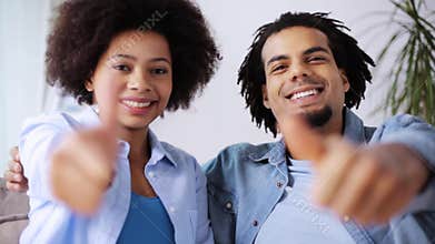Happy couple showing thumbs up at home
