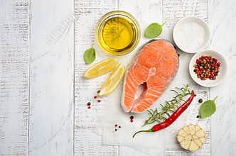 Fresh raw salmon steak with lemon, olive oil and spices on rustic wooden background. Ingredients for making healthy dinner. Health