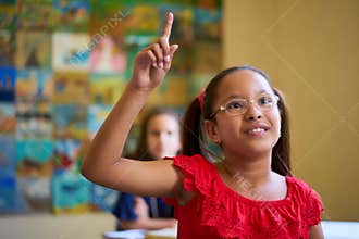 Female Student Raising Hand During Test In Class At School