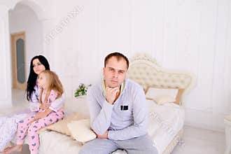 Couple quarrel and child upset, sitting bed in white interior