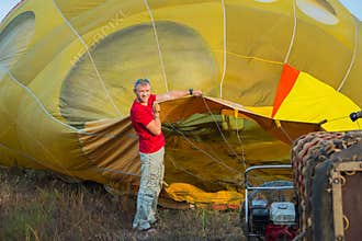 Preparing the baloon. hot air. big baloon. flight. come fly with me. in the field. yellow baloon. summer fun. a men holding baloo