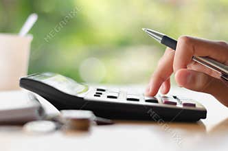 hand holding pen and pressing calculator button for business accounting of finance