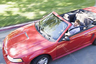 Man driving convertible car smiling