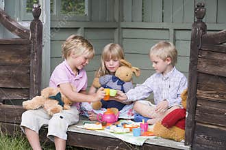 Three young children in shed playing tea