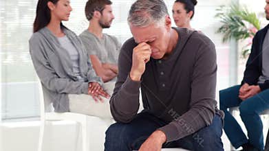 Man comforting another in rehab group at therapy