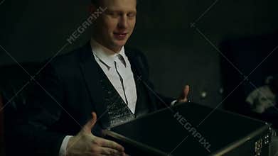 Bright light appearing from the box, and falling on the face of the illusionist.