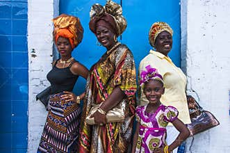 Four female celebrants of Emancipation Day pose against a wall on Picadilly Street, Port-of-Spain, Trinidad on Emancipation Day