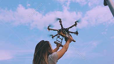 Drone takes off from the hands of a girl near a wind turbine, slow motion.