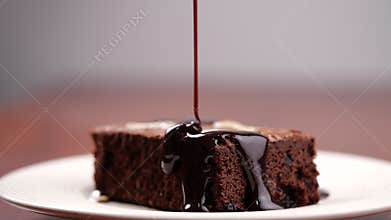 Chocolate pouring on cake in slow motion. Topping chocolate on homemade brownie dessert