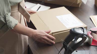 Female online store business owner packing ecommerce parcel shipping box.