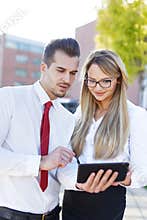 Young businesspeople cooperation by digital tablet outdoors