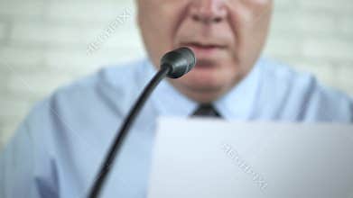Businessman Reading a Document and Speaking on Microphone in a Conference