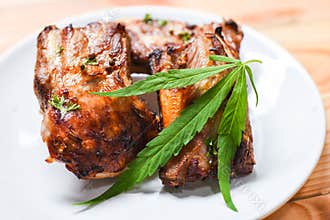 Cannabis food with bbq pork ribs grilled with herbs spices served on white plate - Roasted barbecue pork spare rib and marijuana