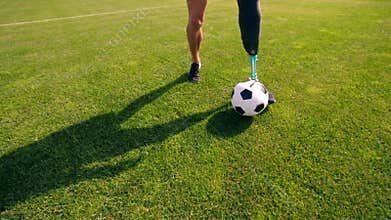 A football is being dribbled by a man with a prosthetic leg