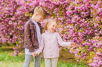 Tender love feelings. Little girl and boy. Romantic date in park. Spring time to fall in love. Kids in love pink cherry