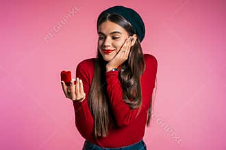 Pretty european young woman in red holding small jewelry box with proposal ring