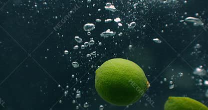 Lime slice fruit splash falling down into white cocktail and water drinking glass, shot in slow motion, fun, nutrition
