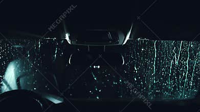Drops flow down the windscreen. Inside view of a windshield car. Dark black cinematic picture. Process stage of