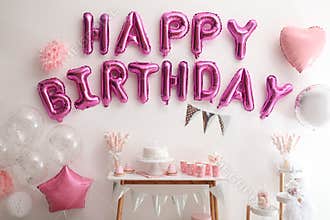 Phrase HAPPY BIRTHDAY made of balloon letters on white wall